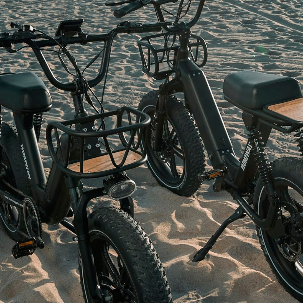 Two Himiway Escape Pro electric bikes on a beach
