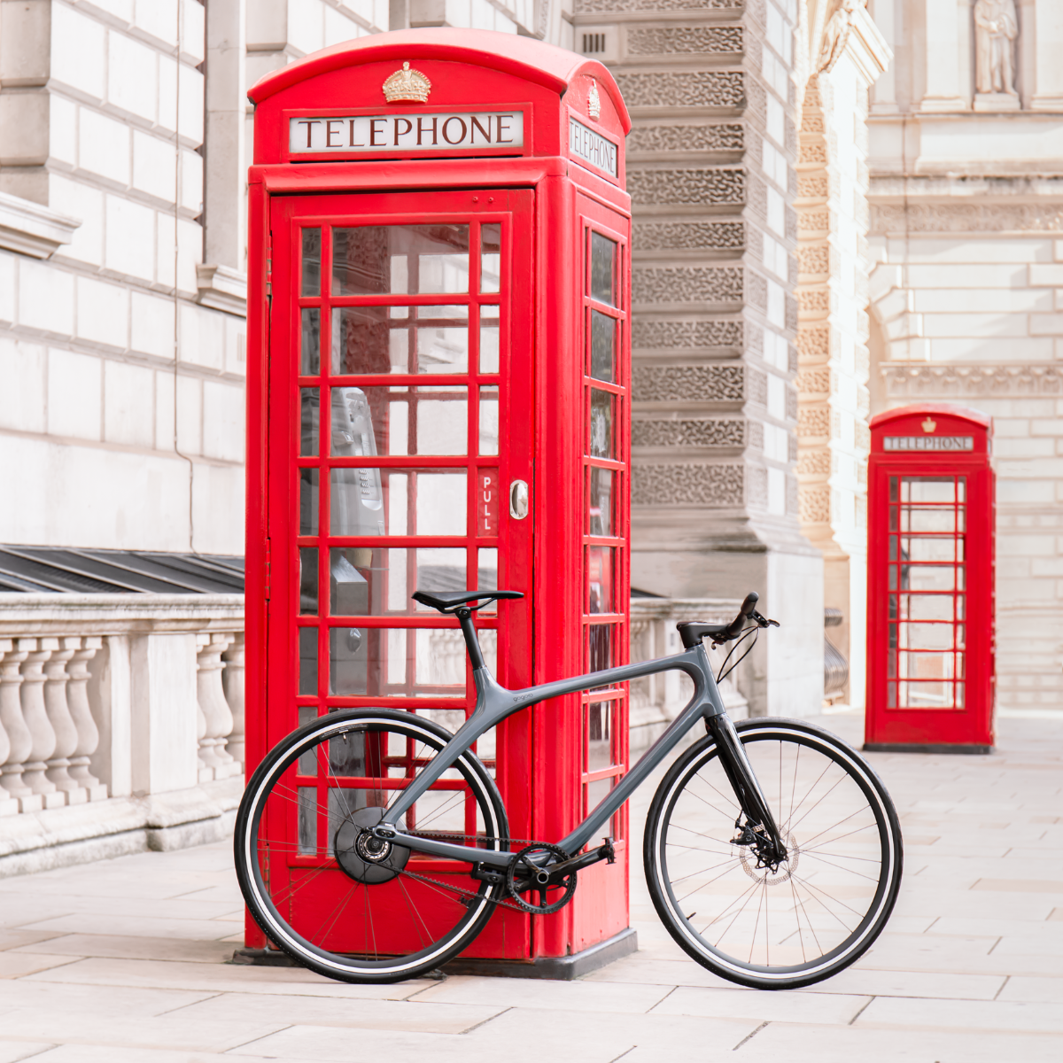 A gray Gogoro Eeyo1 leaning on a red phone box in London