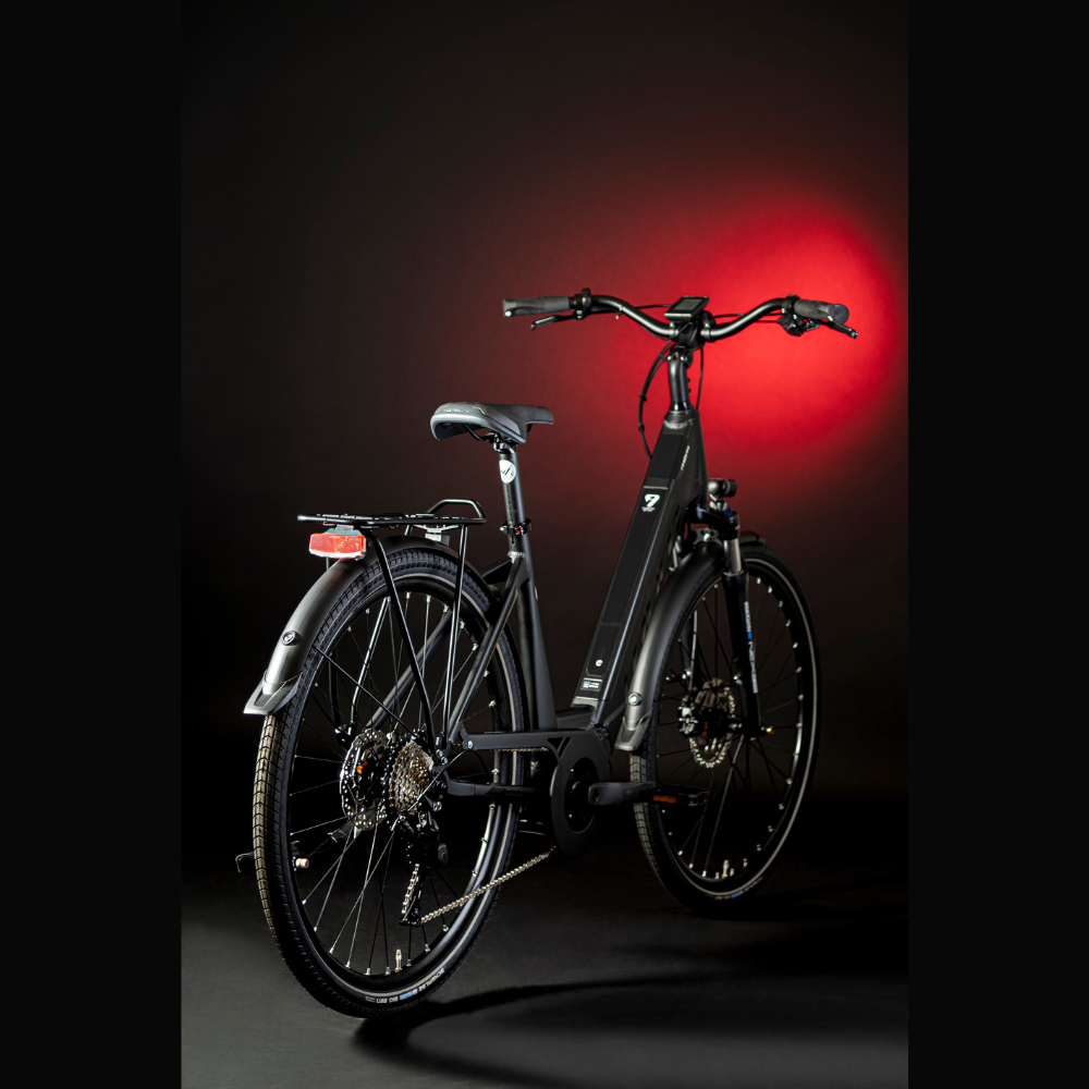 MBM Sinope Step Thru Urban Electric Bike, 15.5MPH Facing oblique right away in a dark studio with red highlighting