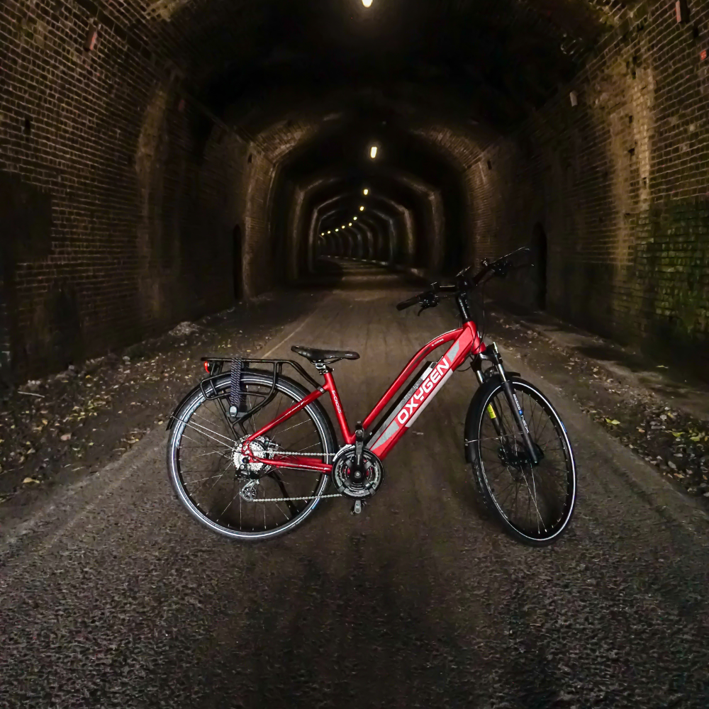 Oxygen S-CROSS ST MKII, Step Thru Electric Bike, Urban, Red, 15.5MPH Close up of the bike in a long atmospheric tunnel  bike on stand and facing right