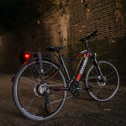 Oxygen S-CROSS CB MKII Trekking Electric Bike, Commuter, Gray 15.5MPH View of the bike from behind and to one side, on its side stand in atmospheric brick tunnel 