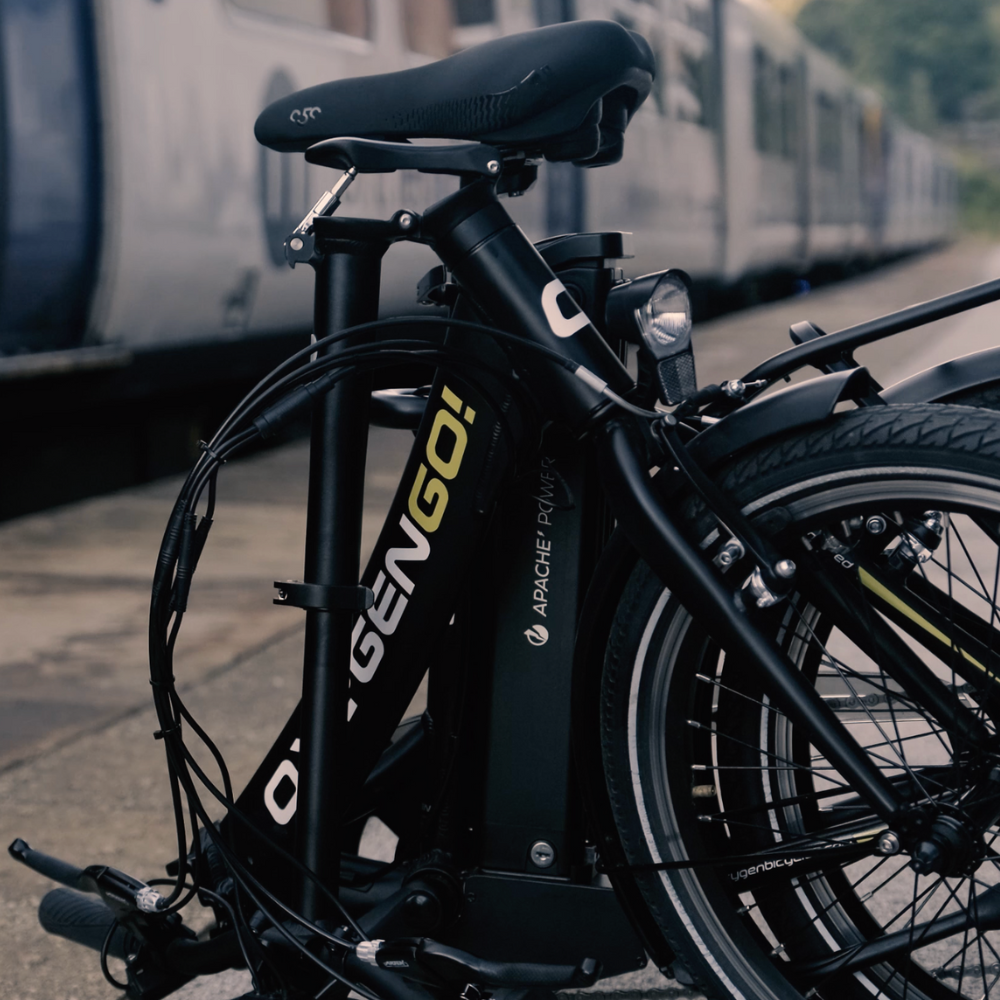 Oxygen Go Folding Step Thru Electric Bike, Urban, Black 15.5MPH folded up on railway platform