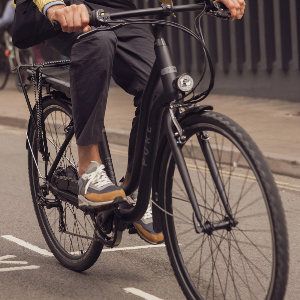 PURE Free City Step Thru Electric Bike, 15.5MPH being ridden in a city, close up of the bike while riding 