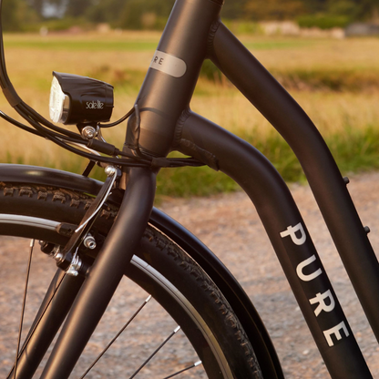 PURE Free City Step Thru Electric Bike, 15.5MPH close up of the frame and light in the country side on a nice day